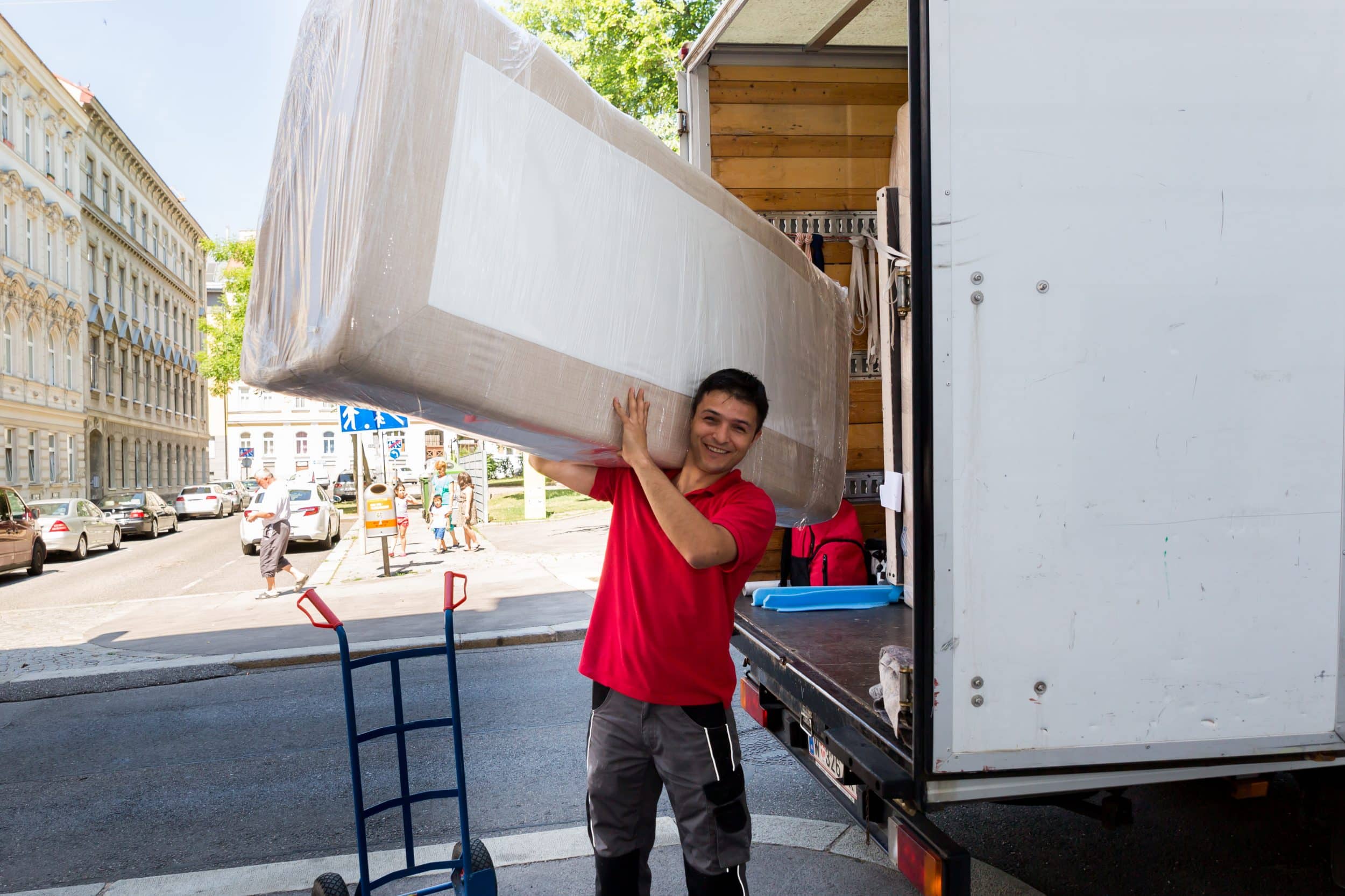wann es sinnvoll ist, eine Umzugsfirma zu beauftragen, Umzugshelfer von Die Umzugsexperten - Umzugsfirma Wien vor Transportwagen