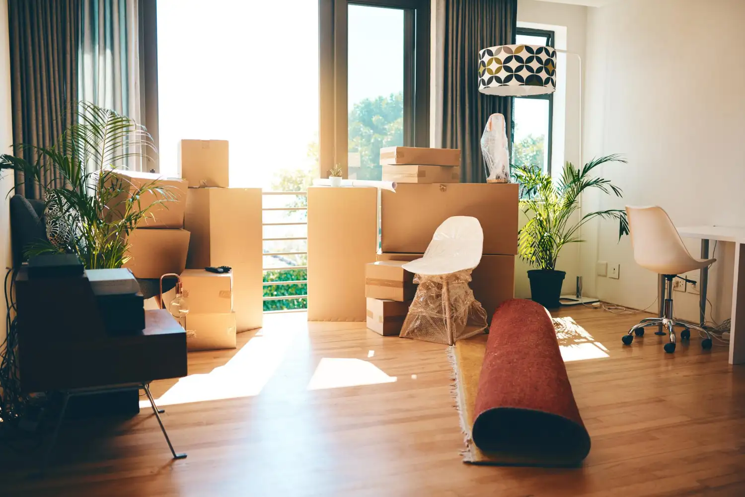 Gestapelte Umzugskartons und eingepackte Möbel in einer hellen Wohnung vor der Wohnungsauflösung