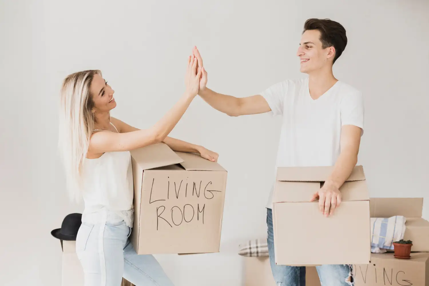 Paar gibt sich ein High Five mit beschrifteten Umzugskartons beim Wohnungstausch Wien
